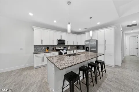 a kitchen with stainless steel appliances granite countertop a table chairs sink refrigerator and microwave