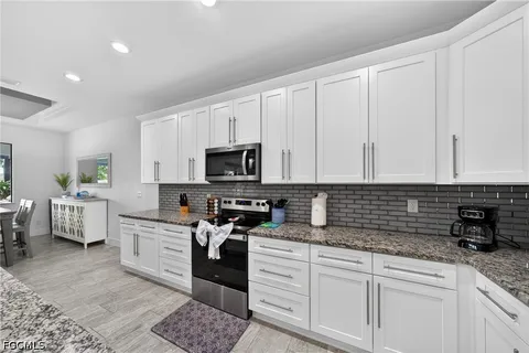a kitchen with stainless steel appliances granite countertop a stove a sink and white cabinets