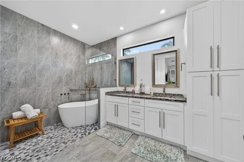 a spacious bathroom with a double vanity sink a mirror and a bathtub