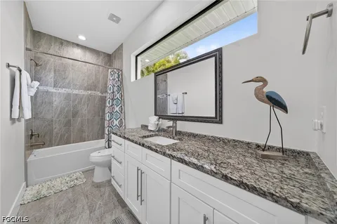 a bathroom with a granite countertop sink a toilet and bathtub