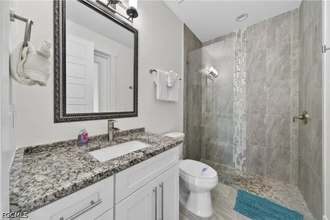 a bathroom with a granite countertop sink toilet and shower
