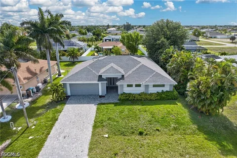 a aerial view of a house next to a yard with plants and large trees