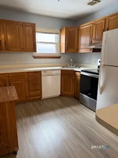 a kitchen with granite countertop a sink cabinets stainless steel appliances and a window
