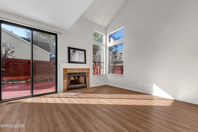 an empty room with wooden floor fireplace and windows