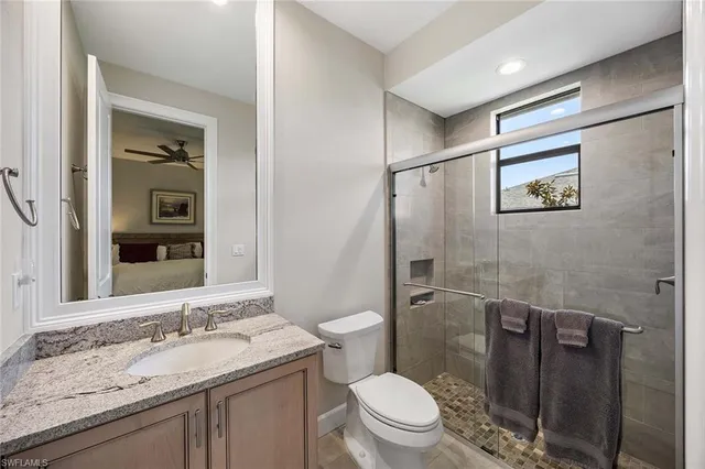 a bathroom with a granite countertop toilet sink and mirror