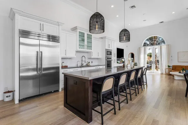 a kitchen with stainless steel appliances granite countertop a refrigerator a stove a sink dishwasher a dining table and chairs with wooden floor