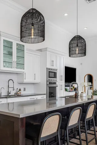 a kitchen with stainless steel appliances granite countertop a sink a microwave a refrigerator and chairs