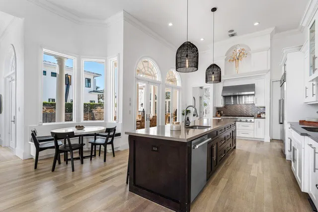 a large kitchen with cabinets a sink a stove and chairs