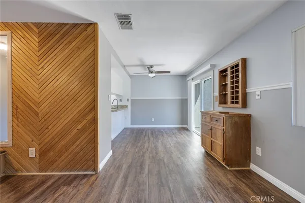 an empty room with wooden floor cabinet and windows