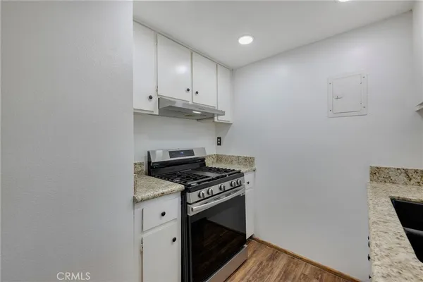 a kitchen that has a sink a stove and wooden floor
