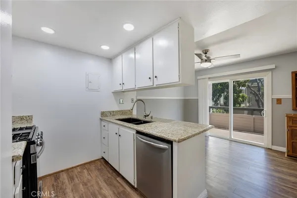 a kitchen with stainless steel appliances granite countertop a refrigerator a sink and white cabinets