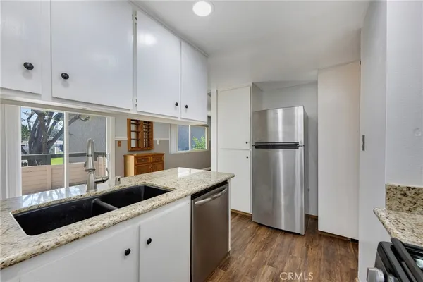 a kitchen with stainless steel appliances granite countertop a sink and a refrigerator