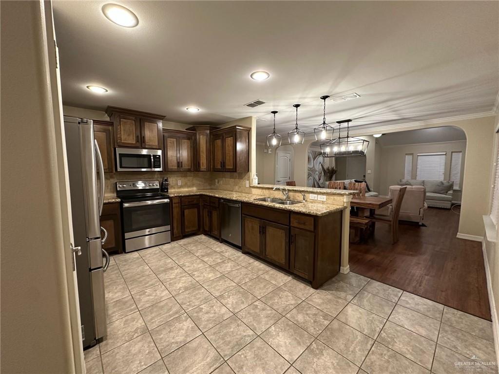 4608 Robin Avenue McAllen, TX 78504 - Photo 3 of 12 Kitchen featuring dark wood cabinetry, light-toned stone countertops, and stainless steel appliances