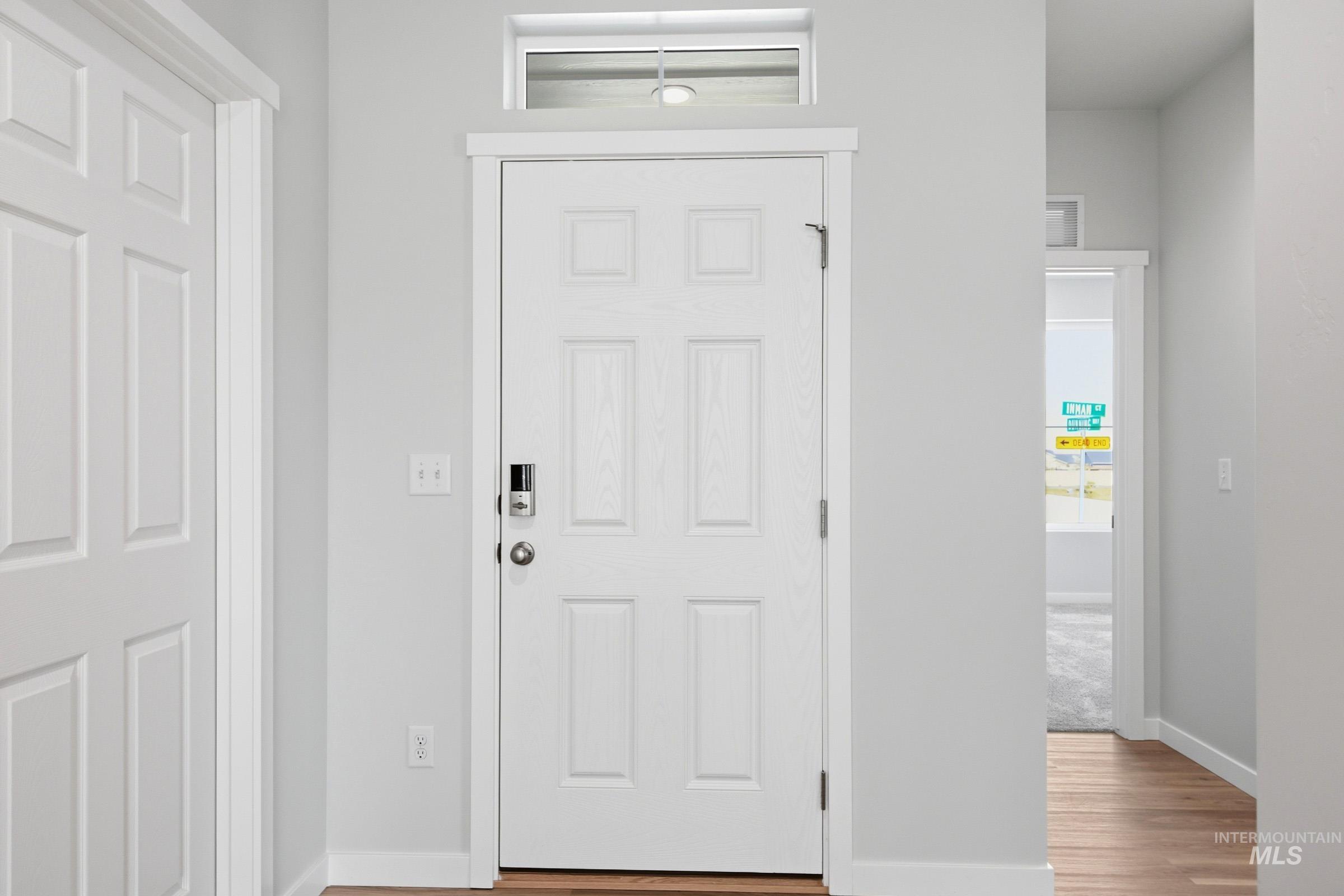 13649 Inman Court Caldwell, ID 83607 - Photo 2 of 22 Entryway featuring a white six-panel door with a digital smart lock, overhead transom window, and wood-finish flooring