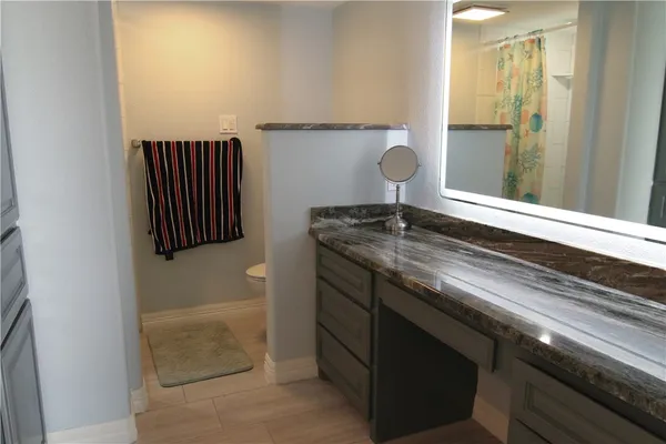 a bathroom with a granite countertop sink a mirror and a bathtub