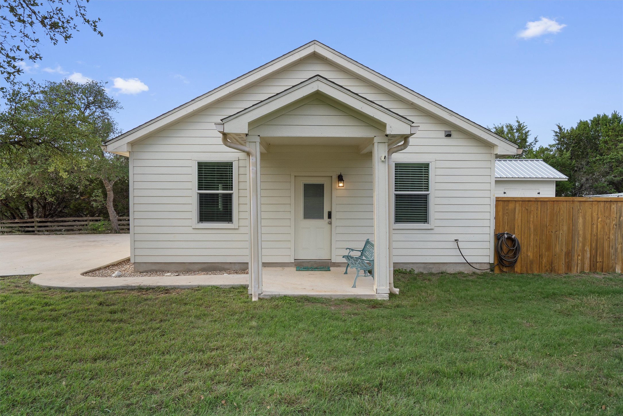 13105 Rooster Springs Road Austin, TX 78737 - Photo 27 of 38 The property features a white exterior with a covered porch entrance and a green lawn