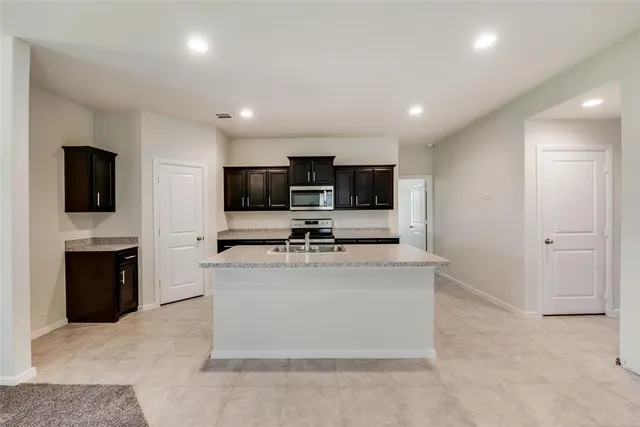 a view of kitchen with microwave stove refrigerator and cabinets