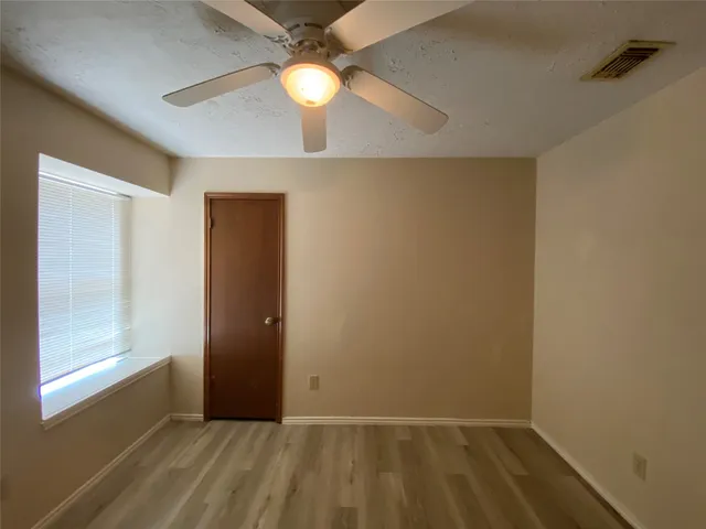 an empty room with windows and fan