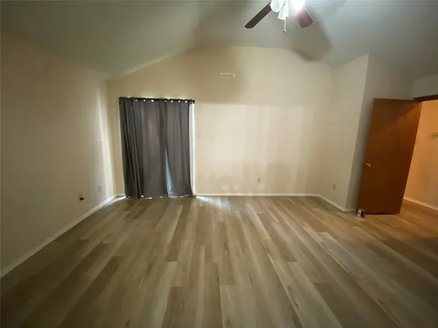 an empty room with wooden floor cabinet and windows