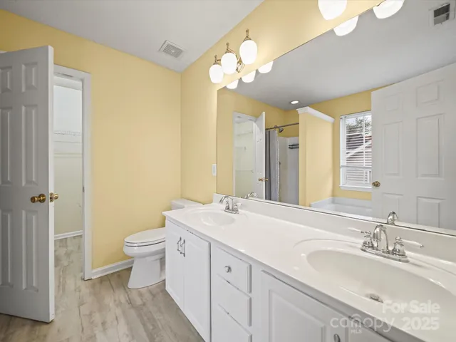 a bathroom with a double vanity sink a toilet and a mirror