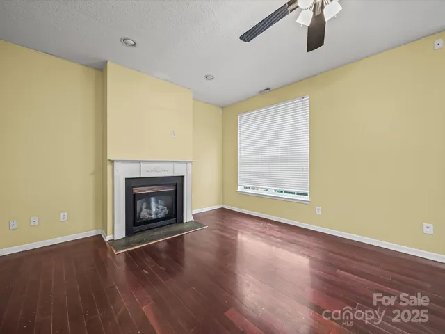 a view of an empty room with wooden floor and a fireplace