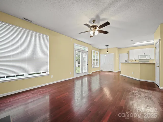 a view of an empty room with window and wooden floor