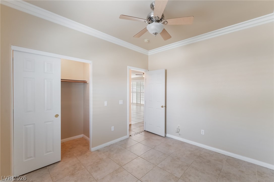 10481 Riverside Park Avenue Las Vegas, NV 89135 - Photo 26 of 51 Bedroom 2 featuring crown molding, ceiling fan, light tile patterned floors, and a walk in closet