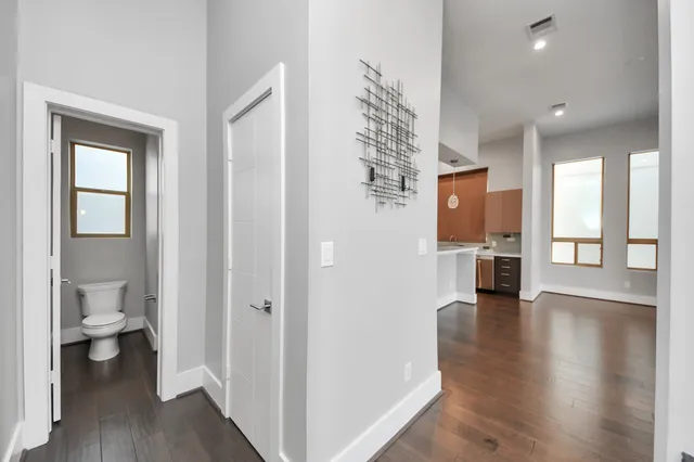 a view of a hallway with wooden floor and a bathroom