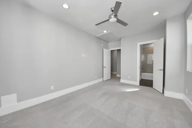 an empty room with a ceiling fan and carpet