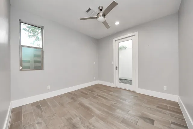 an empty room with windows and fan