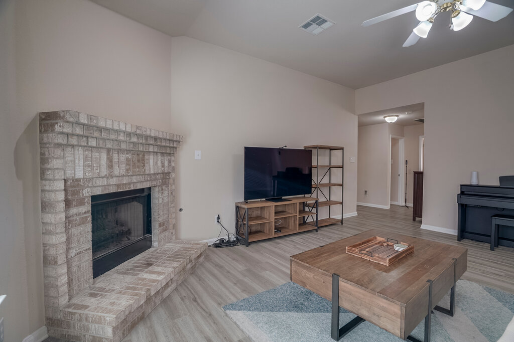 2724 Kickapoo Cavern Drive Pflugerville, TX 78660 - Photo 7 of 24 A classic brick fireplace anchors this inviting living space with durable plank flooring.