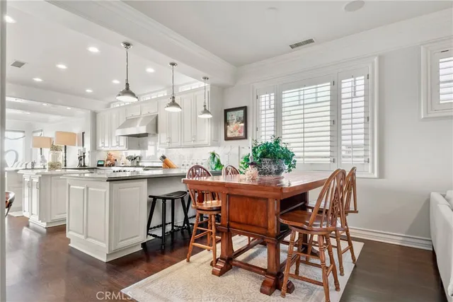 a kitchen with stainless steel appliances granite countertop a stove a sink and white cabinets with wooden floor