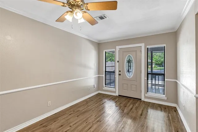 an empty room with wooden floor fan and windows