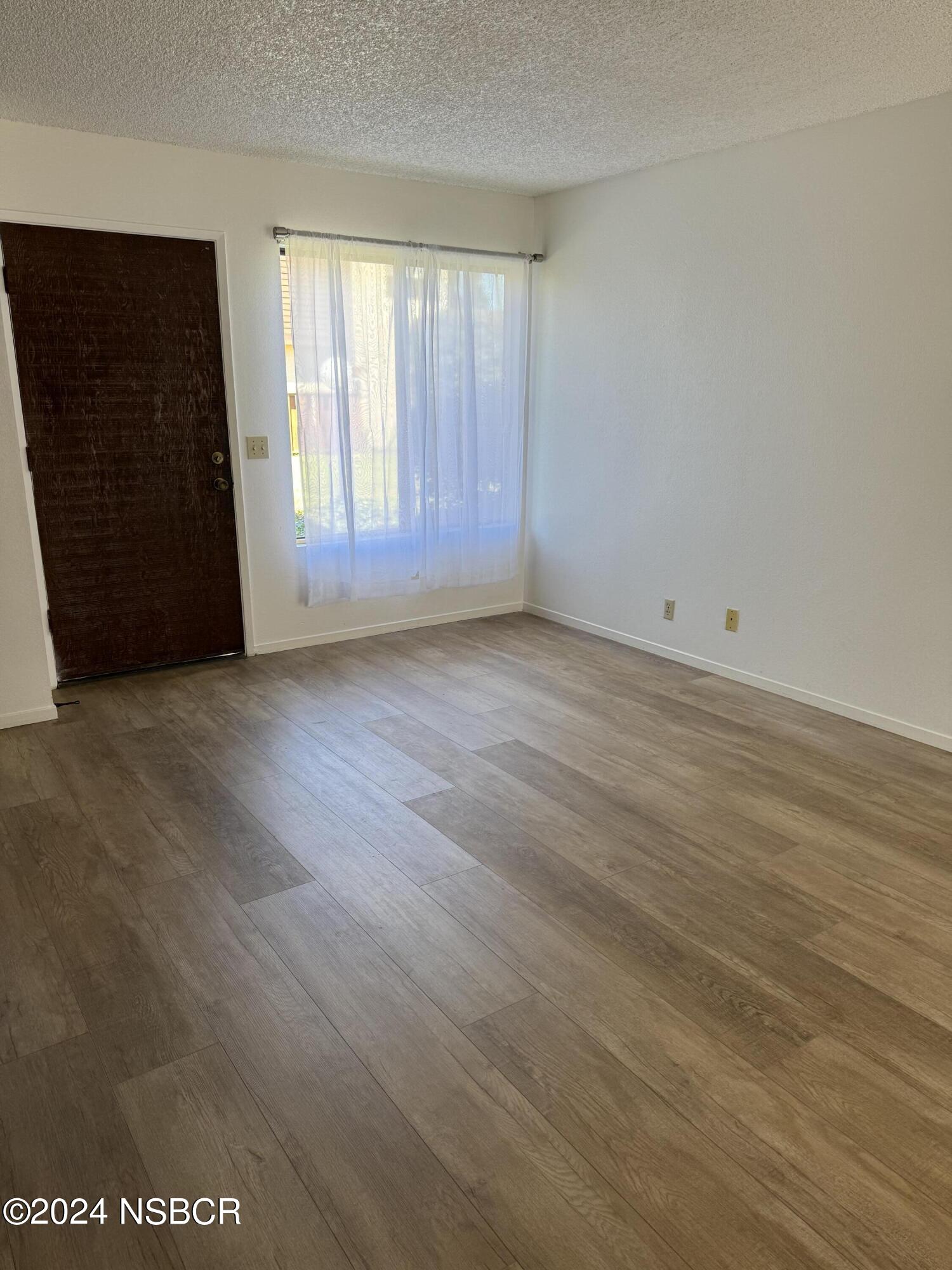 1218 East Walnut Avenue, Unit B Lompoc, CA 93436 - Photo 5 of 11 an empty room with wooden floor and windows