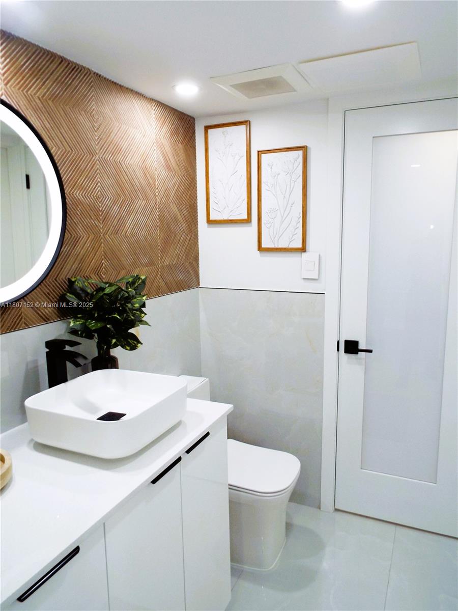 5701 Collins Avenue, Unit 1619 Miami Beach, FL 33140 - Photo 31 of 77 a bathroom with a sink a toilet and mirror