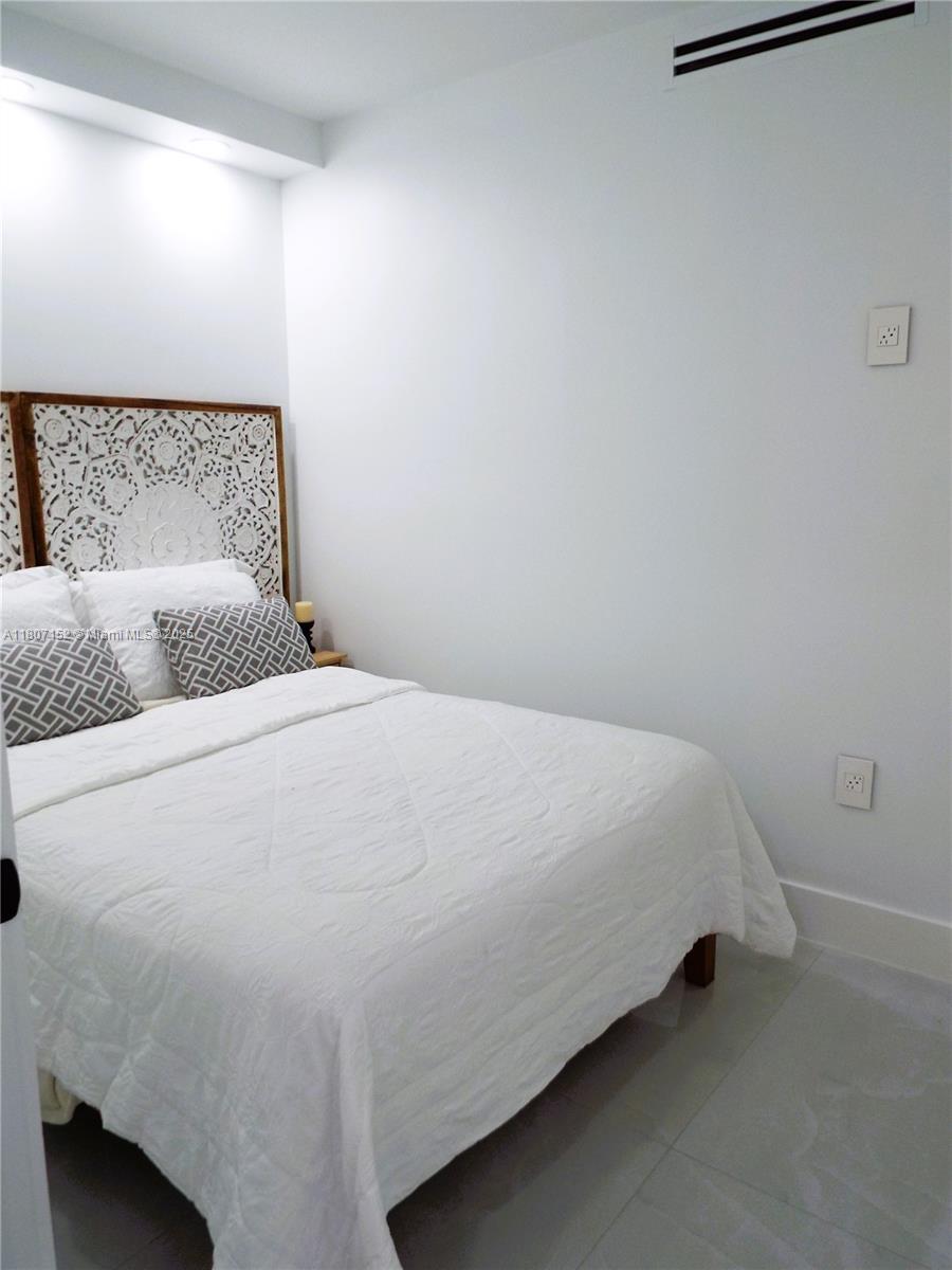 5701 Collins Avenue, Unit 1619 Miami Beach, FL 33140 - Photo 33 of 77 a bedroom with a bed and a night stand