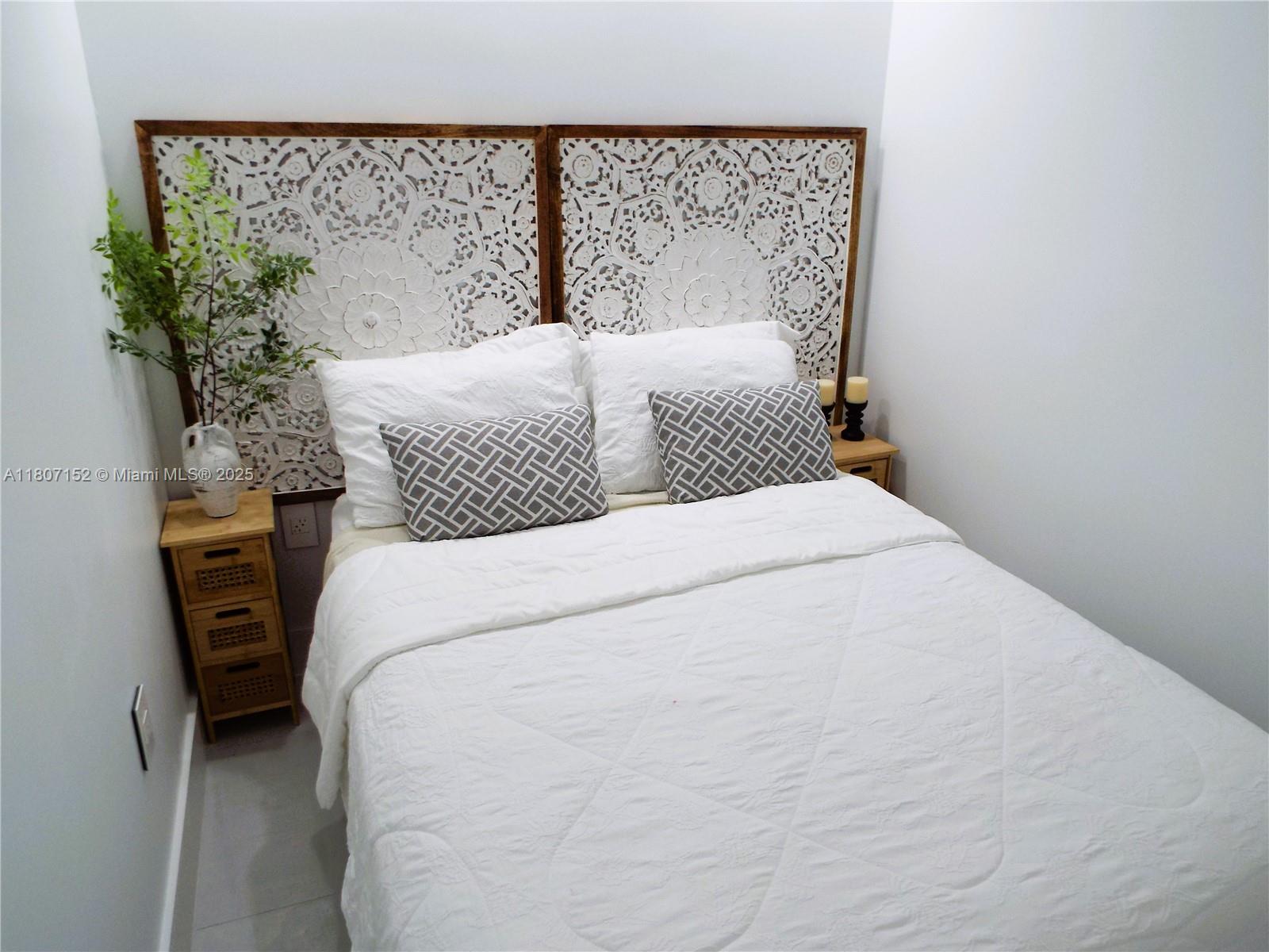 5701 Collins Avenue, Unit 1619 Miami Beach, FL 33140 - Photo 35 of 77 a large bed sitting in a bedroom next to a small yard