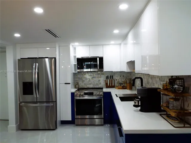 a kitchen with stainless steel appliances kitchen island granite countertop a sink and a refrigerator
