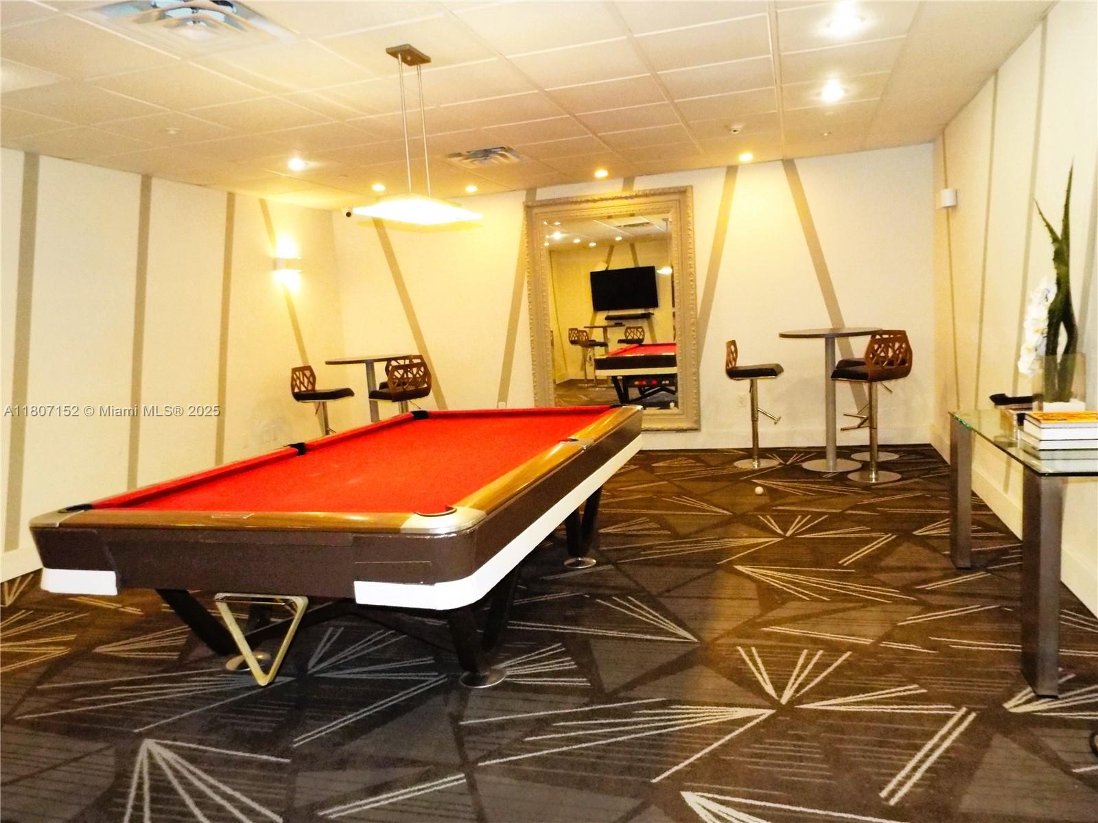 5701 Collins Avenue, Unit 1619 Miami Beach, FL 33140 - Photo 52 of 77 a room with table chairs and a flat screen tv