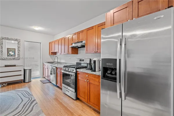 a kitchen with stainless steel appliances granite countertop a refrigerator a stove and a sink with cabinets