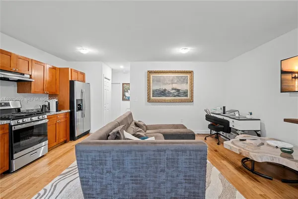 a living room with stainless steel appliances furniture stove top oven and cabinets