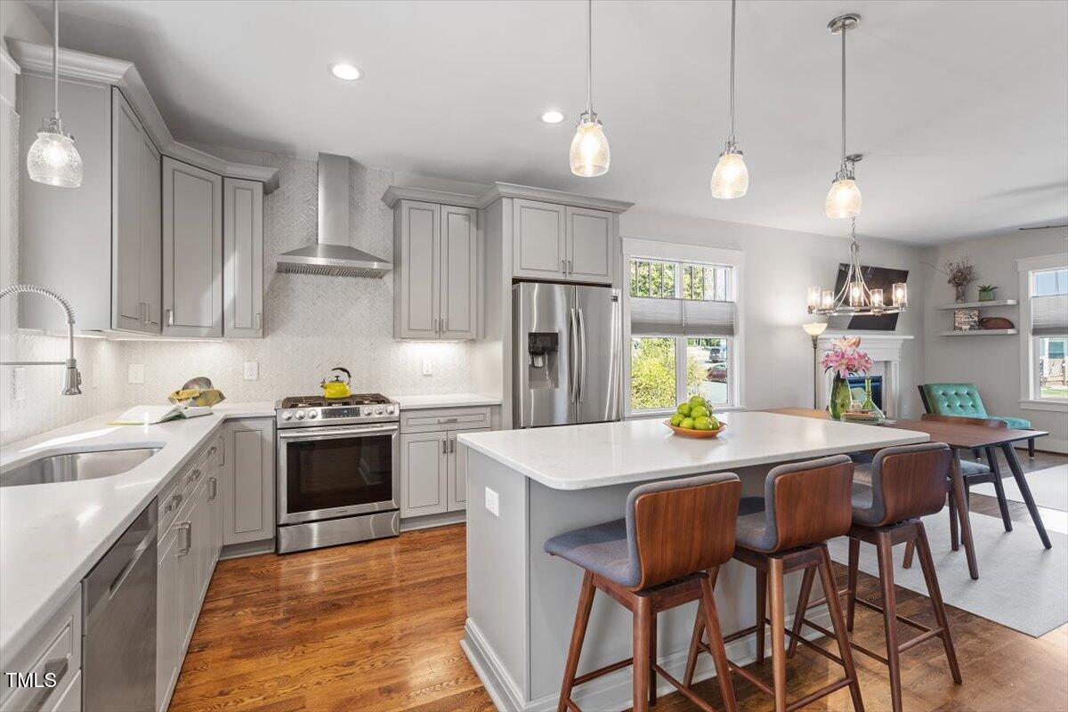 700 Coleman Street Raleigh, NC 27610 - Photo 14 of 44 a kitchen with stainless steel appliances granite countertop a stove a sink dishwasher a refrigerator and a dining table with wooden cabinets