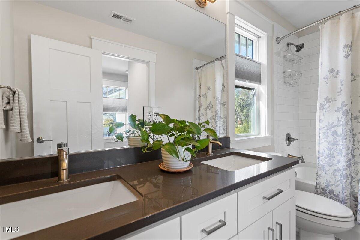 700 Coleman Street Raleigh, NC 27610 - Photo 33 of 44 a bathroom with a granite countertop sink a toilet and a mirror