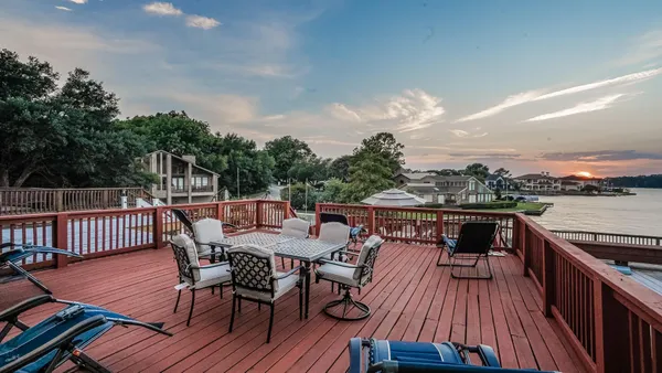 a view of a roof deck with table and chairs a barbeque with wooden floor and fence