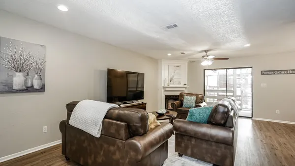 a living room with furniture a flat screen tv and wooden floor