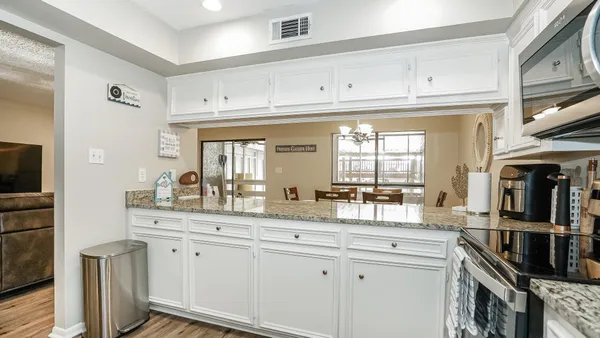 a kitchen with granite countertop a sink cabinets stainless steel appliances and a window