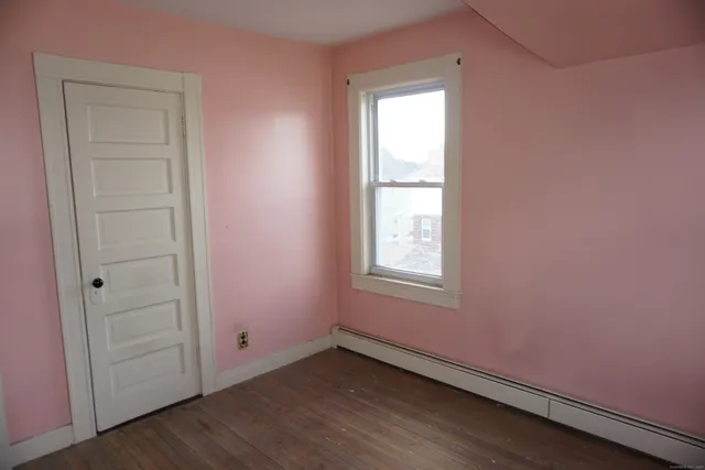 an empty room with wooden floor and window
