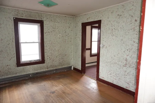 an empty room with wooden floor closet and windows
