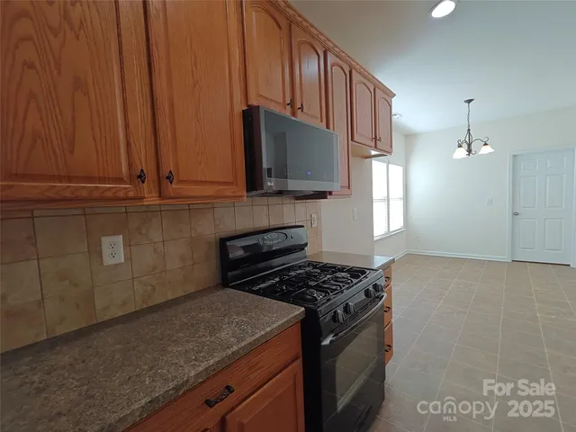 a kitchen with stainless steel appliances granite countertop a stove a sink and a microwave