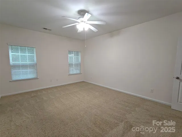 an empty room with windows and chandelier fan